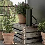 Stelton Bloom Watering Can in matte dark green powder-coated stainless steel with long slender spout and seamless handle design.