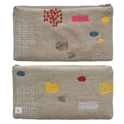 Patches Pouch by K Studio made of natural flax linen with colorful stitched patch motifs, slim rectangular shape, and zip closure on a neutral background.
