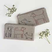 Dogs Pouch by K Studio in natural flax linen with embroidered line-drawn dogs, quilted construction, zippered closure, and dotted cotton lining.