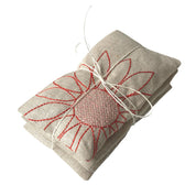 Blooms Sachet Set by K Studio with three flax linen sachets embroidered with colorful floral designs, filled with lavender and arranged on a white background.