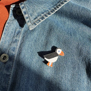 Kauniste Puffin Pin, a sustainable maple wooden pin featuring a black-and-white Atlantic puffin with orange beak and feet.
