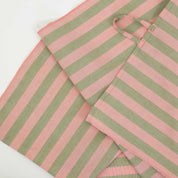 Martina Kitchen Towel by A World of Craft with wide coral and olive green handwoven cotton stripes, folded to showcase the textured reps weave and bold striped pattern.