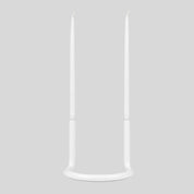 Architectmade Gemini Candleholder by Peter Karpf in matte white stainless steel, styled with matching white taper candles in a sculptural curved form.