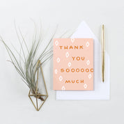 Thank You Sooo Much Card with orange hand-lettered text and white diamond shapes on a peachy pink background.
