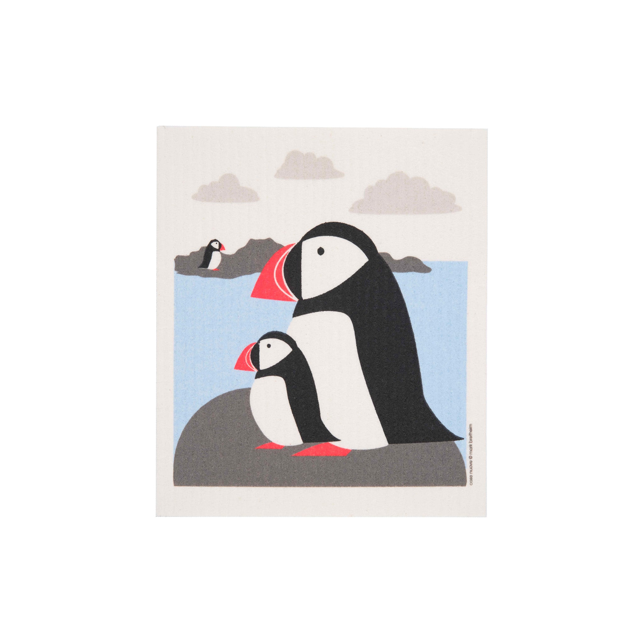 Puffins Swedish Dishcloth by Cose Nuove featuring three black-and-white puffins with bright orange-red beaks perched on gray coastal rocks beside a pale blue sea.