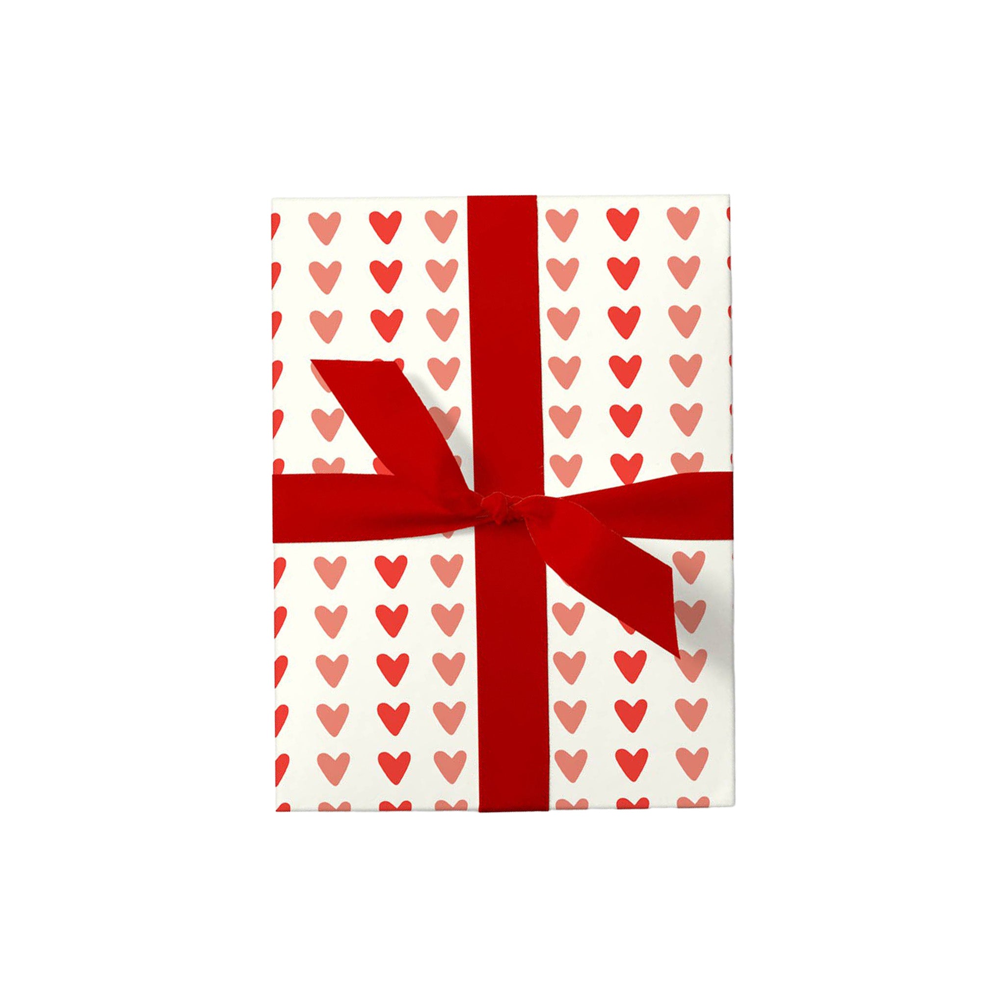 Hearts Gift Wrap with red and blush heart pattern on creamy white paper, wrapped around a gift and finished with a bold red ribbon.