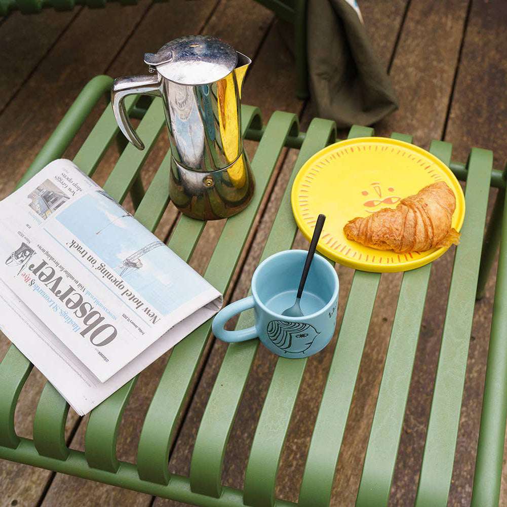 Teal-blue Donna Wilson stoneware mug with two debossed illustrated faces chatting on the side.