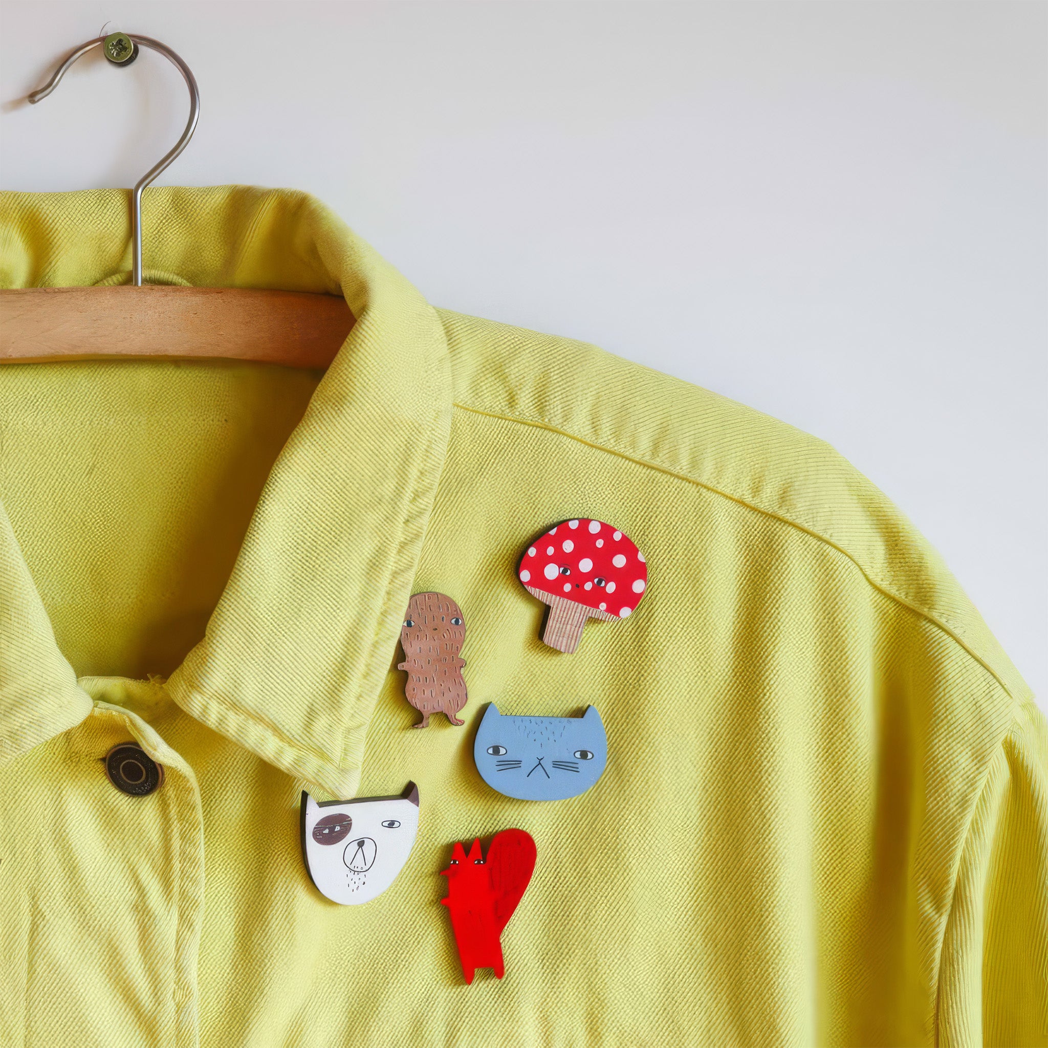 Donna Wilson Toadie Brooch Pin featuring a red and white spotted mushroom character with a friendly face, made from sustainably sourced beech wood with a metal butterfly clutch backing.