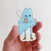 Cozy Maine Sticker by Allison McKeen featuring a blue illustrated character holding a warm mug with “Maine” lettering.