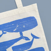 Whale Pod Tote Bag by Kautzi Illustrations with periwinkle blue whales screen-printed on natural cotton.