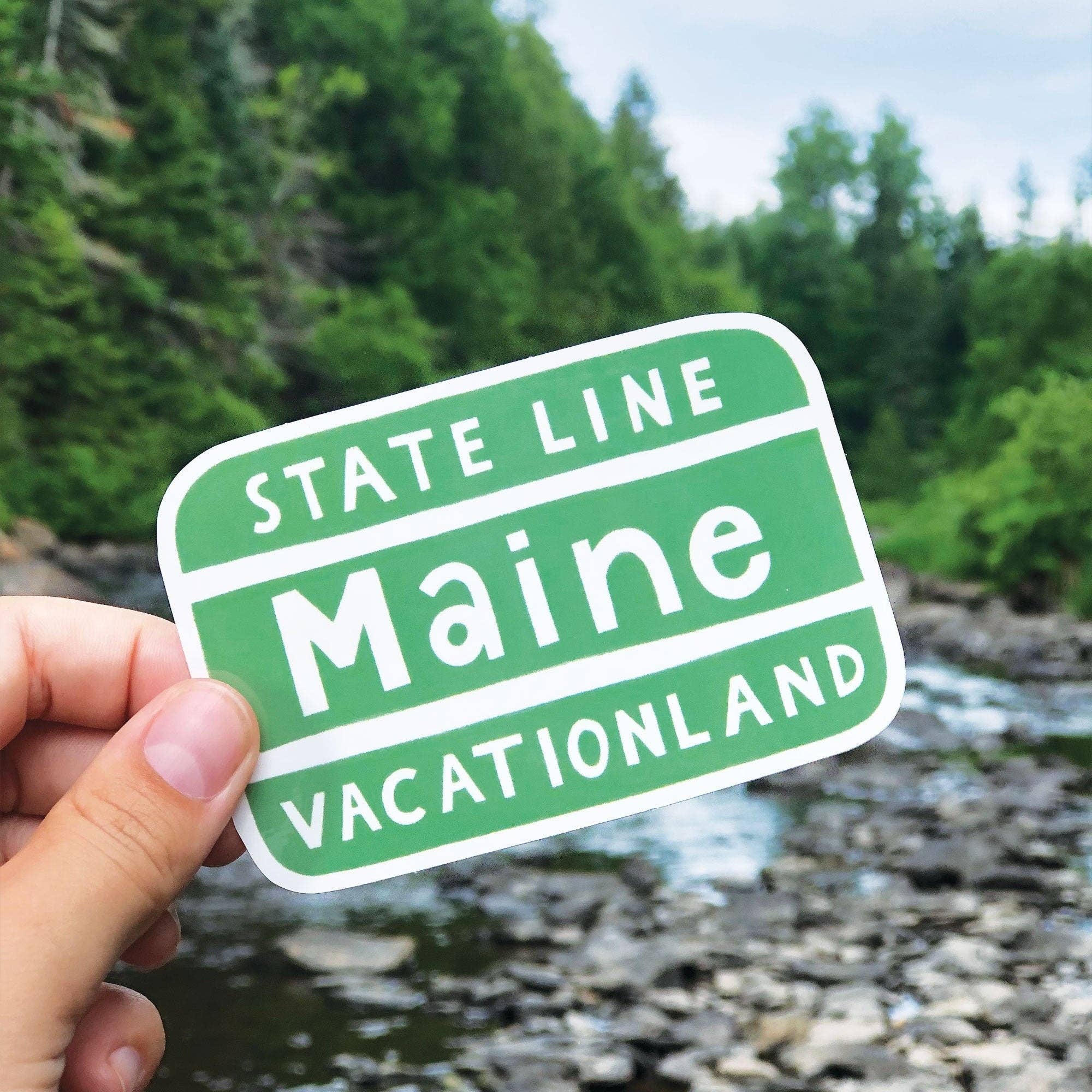 Little Something Co. Maine Vacationland Sign Sticker featuring the iconic green and white Maine State Line Vacationland sign.