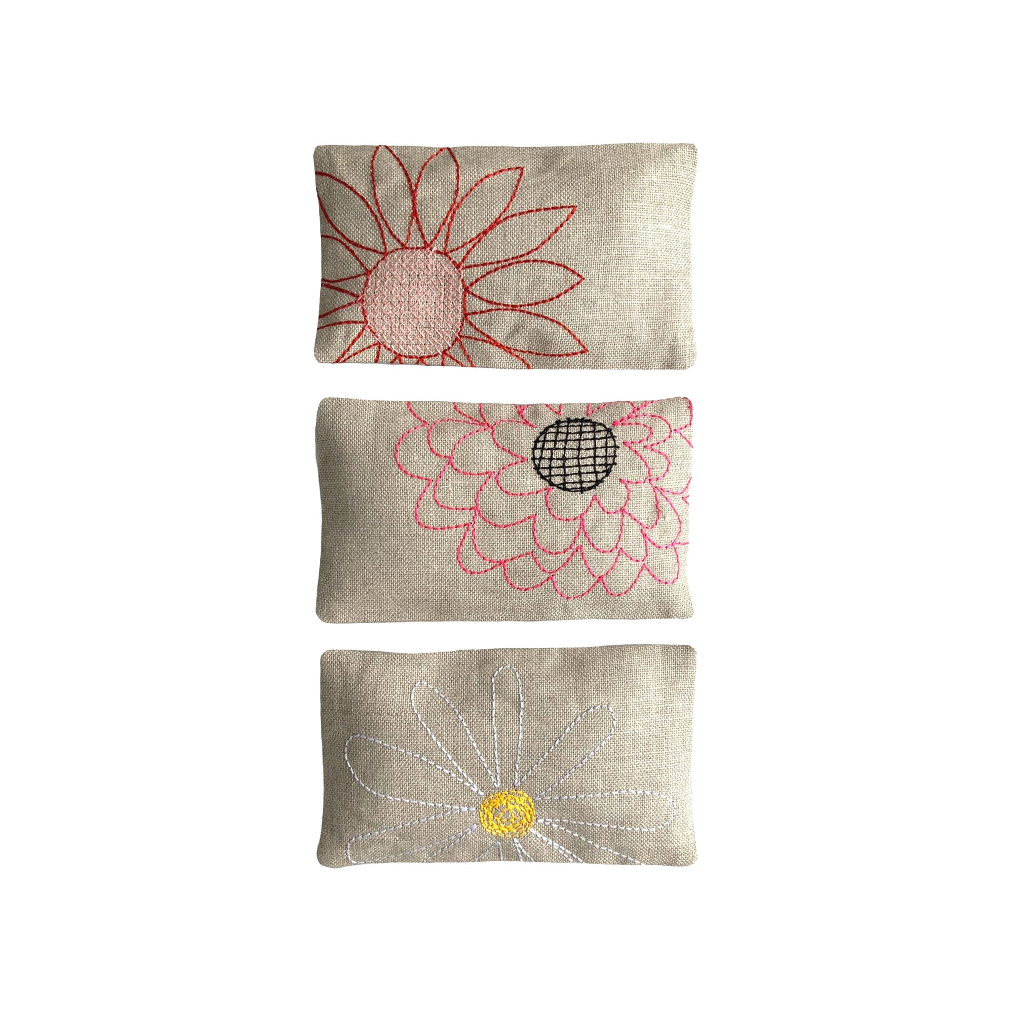 Blooms Sachet Set by K Studio with three flax linen sachets embroidered with colorful floral designs, filled with lavender and arranged on a white background.