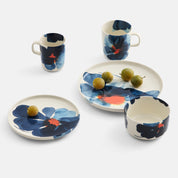 Marimekko Valssi Dinnerware with bold floral print in blue and orange on white stoneware.