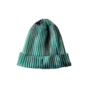 Evergreen Hand-Dyed Beanie Hat by Merle Works featuring a ribbed cotton-blend knit in varied shades of forest green, mint, and teal with darker hand-dyed speckles and a folded cuff.