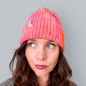 Shortcake Hand-Dyed Beanie Hat by Merle Works in strawberry pink with apricot, coral, and raspberry accents, featuring a ribbed cotton-blend knit, folded cuff, and woven logo tag.