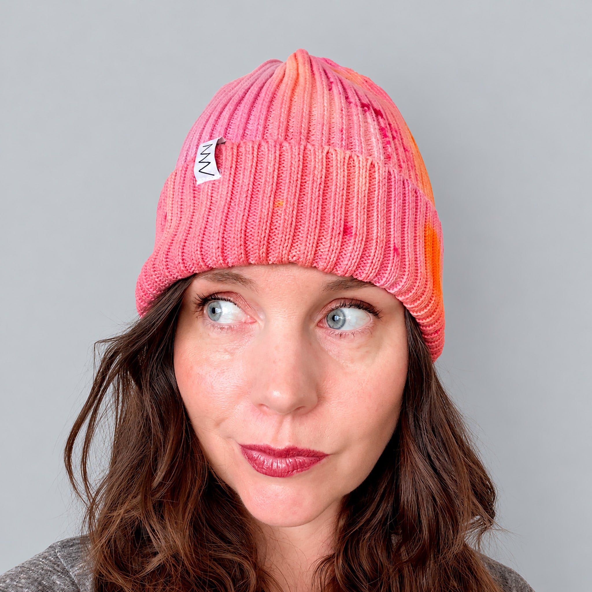 Shortcake Hand-Dyed Beanie Hat by Merle Works in strawberry pink with apricot, coral, and raspberry accents, featuring a ribbed cotton-blend knit, folded cuff, and woven logo tag.
