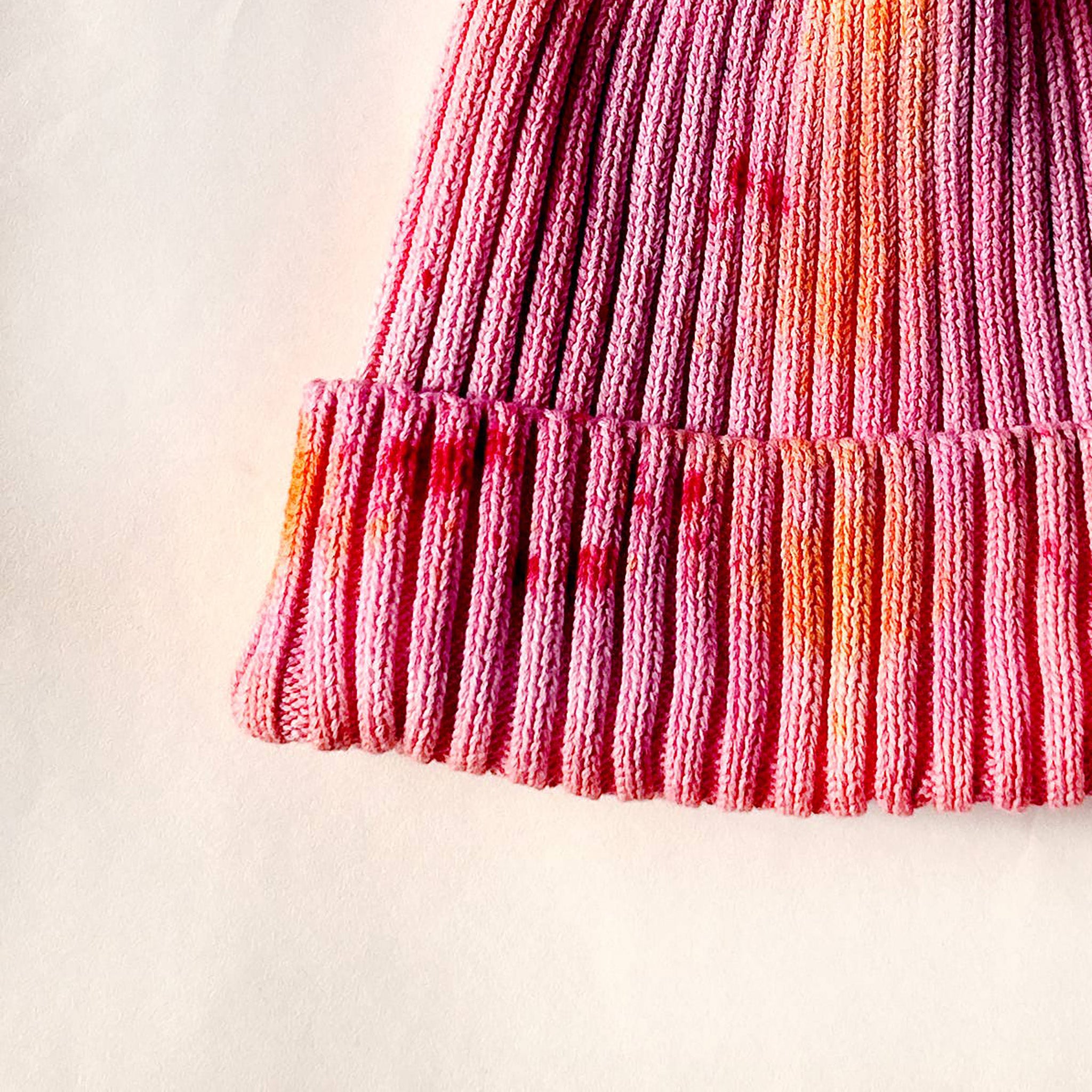 Shortcake Hand-Dyed Beanie Hat by Merle Works in strawberry pink with apricot, coral, and raspberry accents, featuring a ribbed cotton-blend knit, folded cuff, and woven logo tag.