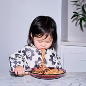Long sleeve smock bib in six artist-designed colorways. Waterproof, recycled fabric, fits 6 months–3 years—extra coverage for mealtime and crafts.