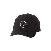 Mochi Kids Happy Dad Hat in Black / White with embroidered smiley face, curved brim, and adjustable fabric strap with brass slider closure.