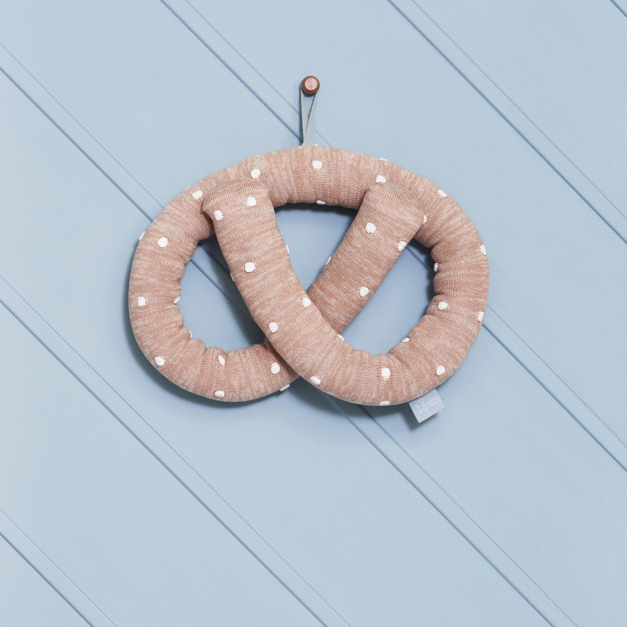 OYOY Sweet Pretzel Cushion in caramel cotton knit with dotted design, cuddly pretzel pillow for kids or adults.