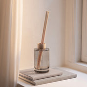 Ro Scent Diffuser by Skandinavisk with Scandinavian-inspired fragrance notes of cut grass, cucumber, wild violets, and fallen leaves in a minimalist glass diffuser vessel.