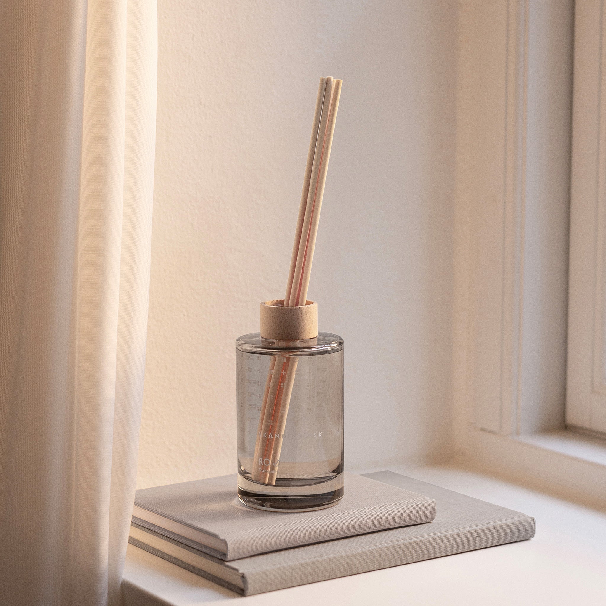 Ro Scent Diffuser by Skandinavisk with Scandinavian-inspired fragrance notes of cut grass, cucumber, wild violets, and fallen leaves in a minimalist glass diffuser vessel.