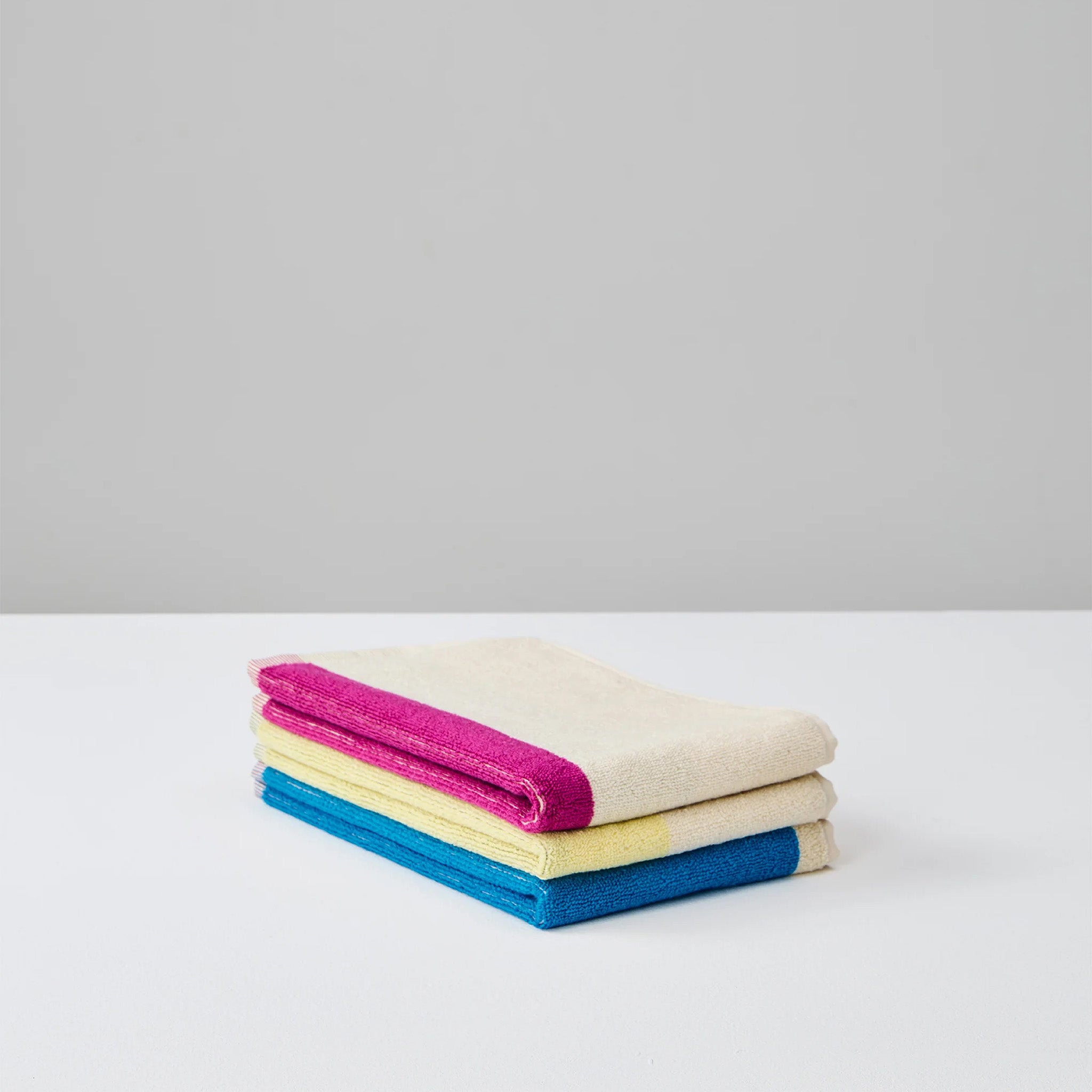 Aqua Fuchsia Yellow Guest Towel Set by SUITE702 with three reversible colorful guest towels.