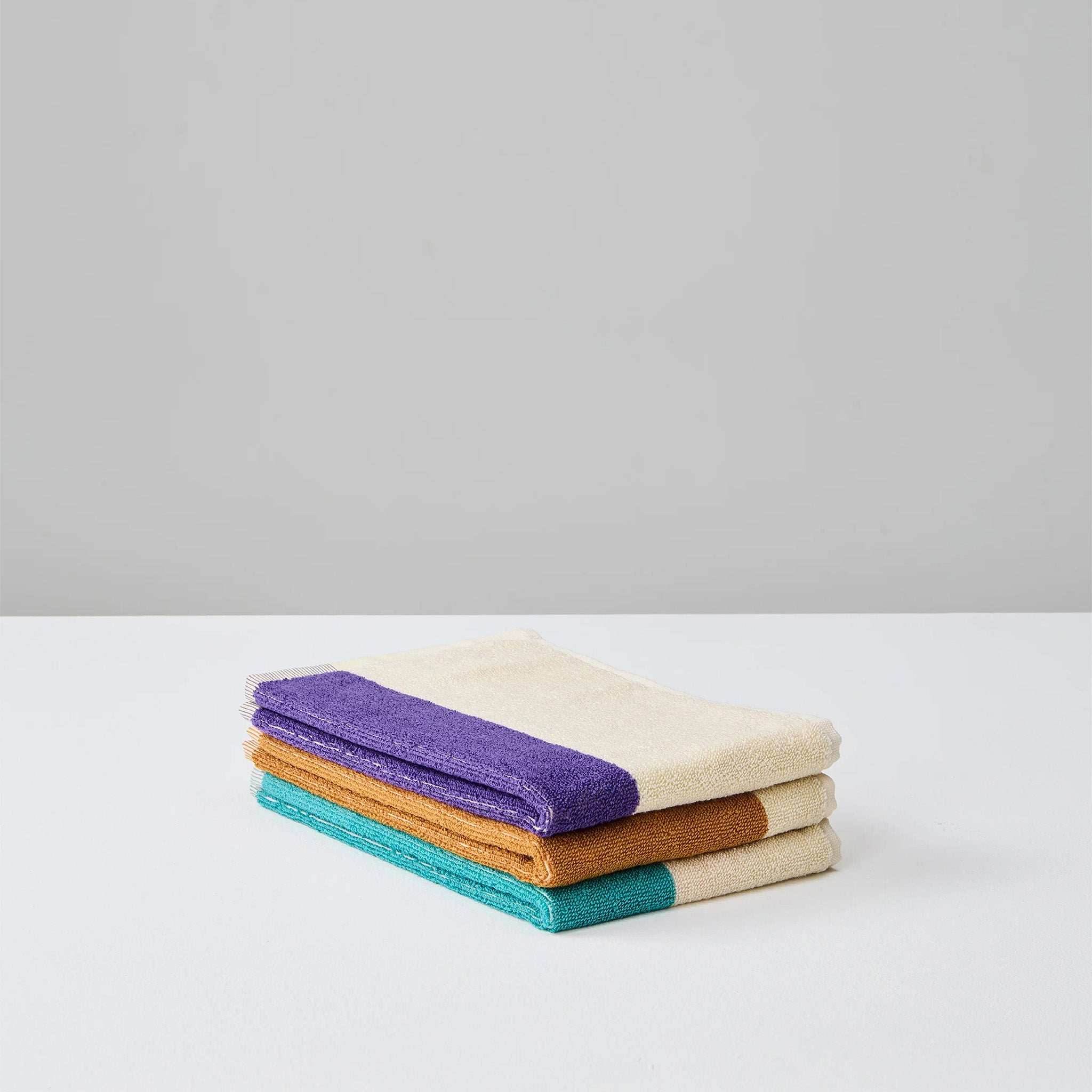 Turquoise Purple Toffee Guest Towel Set by SUITE702 with three reversible colorful guest towels.