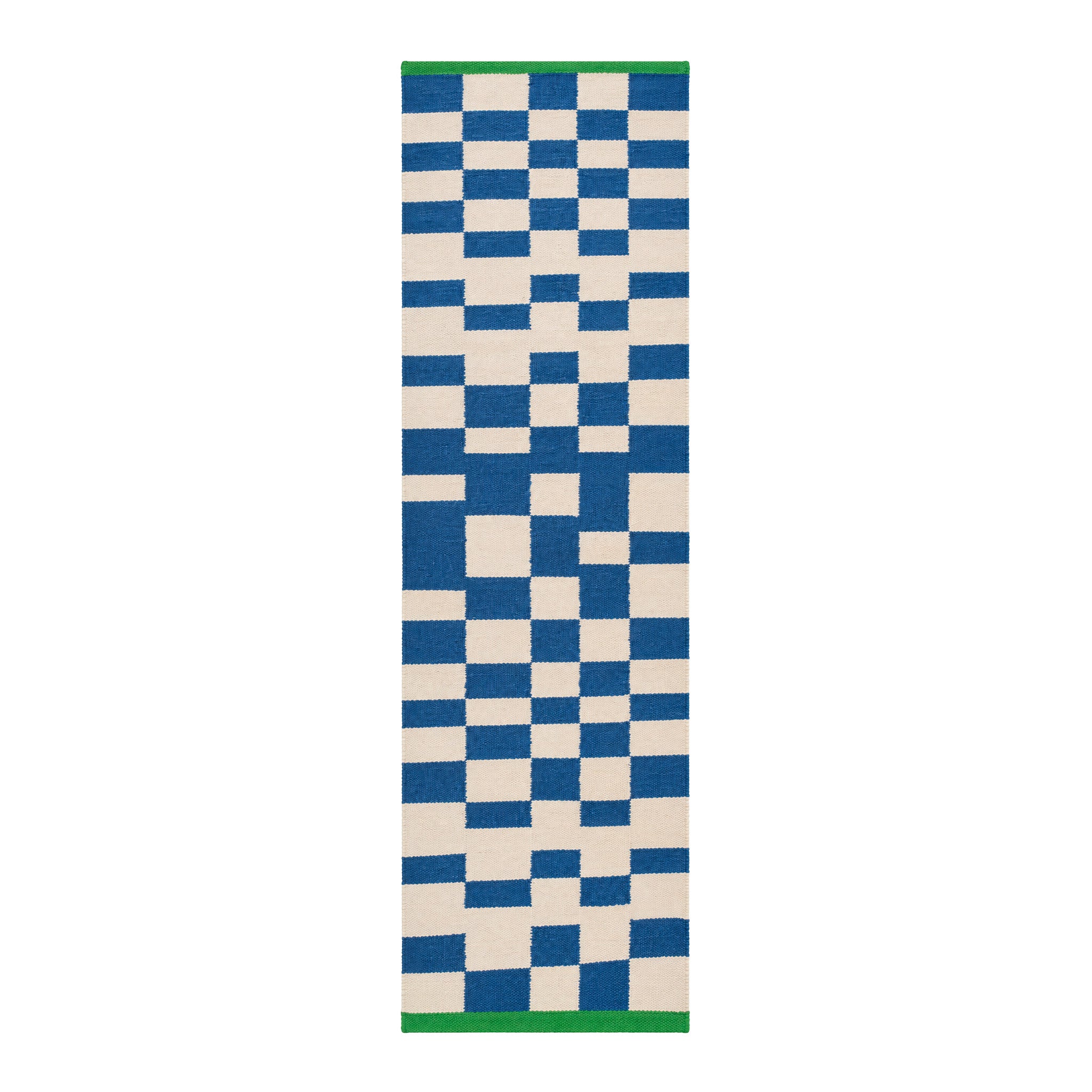 Blox Rug by Tarta Gelatina in Bleu, featuring an irregular blue and cream checkerboard pattern with bright green trim at both ends. Handmade from 100% cotton.