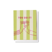 You Did It Card with pink high-five illustration and lettering on a lime green and cream striped background.