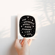 Worthwhile Paper The Universe Needs You Card featuring “The Universe Needs You” lettering surrounded by a cosmic pattern of stars and sparkles.